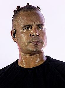 close-up of Ray Slijngaard wearing a black t-shirt and an earpiece, with a sweaty face