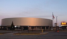 A brightly lit hockey arena, clad in metal panels.