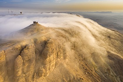 Nevoeiro de advecção levado por um vento catabático em Makhtesh Ramon, um grande “circo de erosão” (desfiladeiro) no deserto do Neguev, Israel. Foto tirada com um drone. O nevoeiro do tipo advectivo ocorre quando o ar úmido passa sobre uma superfície fria por advecção (vento) e é resfriado. É comum quando uma frente quente passa sobre uma área com significativa camada de neve. É mais comum no mar quando o ar úmido encontra águas mais frias, incluindo áreas de afloramento de água fria. Uma diferença de temperatura forte o suficiente sobre a água ou o solo descoberto também pode causar nevoeiro de advecção. (definição 5 417 × 3 611)