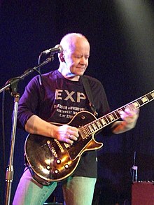 middle-aged white male playing guitar onstage