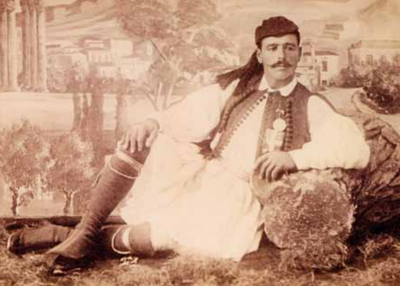 Un homme en habit traditionnel est à moitié allongé et regarde vers la droite.