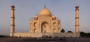 Lado ocidental do Taj Mahal na hora dourada, um mausoléu de mármore branco-marfim na margem direita do rio Jamuna em Agra, Utar Pradexe, Índia. Foi encomendado em 1631 pelo quinto imperador Mogol, Xá Jeã, para abrigar o túmulo de sua amada esposa, Mumtaz Mahal; também abriga o túmulo do próprio Xá Jeã. O túmulo é a peça central de um complexo de 17 hectares, que inclui uma mesquita e uma casa de hóspedes, e está situado em jardins formais delimitados em três lados por um muro com ameias. (definição 12 391 × 5 777)