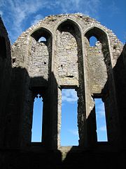 Photographie couleurs d'un chevet d'église dans lequel une partie des verrières a été murée.