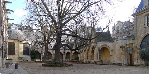 Le cloître de l'église Saint-Séverin vue de la rue : à gauche la façade sud de l'église et à droite le presbytère. Au centre les vestiges du cimetière transformé en jardin et des galeries qui servaient de charniers.