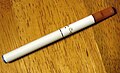 Cigarette électronique de première génération à déclenchement automatique, imitant l'aspect d'une vraie cigarette, avec indicateur lumineux à l'extrémité.