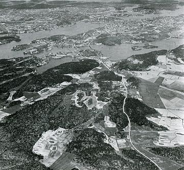 Stockholm från sydväst från 1000 meters höjd år 1898. Den vita linjen är Södertäljevägen. Det ljusa område i förgrunden till vänster är jordbrukslandskap kring dagens Midsommarkransen. Mot Årstaviken ligger liksom idag ett skogsbälte. Den stora landmassan i bakgrunden är Södermalm. Jämför med motsvarande, samtida kartbilden till höger. Ballongfoto av Oscar Halldin 1898, karta av Topografiska corpsen 1861.