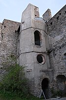 Tower attached to a wall with several windows on each floor.