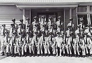 Group portrait of uniformed staff in front of building