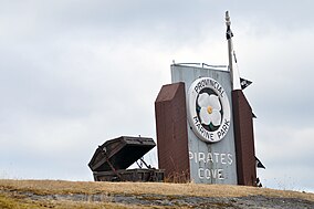 A park sign with a treasure chest next to it on top of a small hill