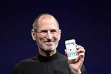 Homme souriant tenant un téléphone dans sa main.