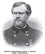 Black and white image shows a bearded man in a dark military uniform with two rows of buttons