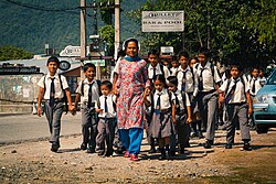 Teacher in Nepalese dress and a group of uniformed schoolchildren of different ages
