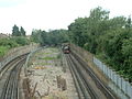 From the A12 looking south of Newbury Park showing the present route to Gants Hill diverging from the former alignment to Ilford and Seven Kings. An eastbound train has just emerged from the portal.