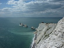 Photographie couleur de falaises blanches et de rochers dans la mer.