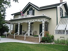 A nineteenth century wooden rural home of some elegance, with a British Ensign flag mounted from its veranda.