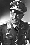 A man wearing a military uniform, peaked cap, and an Iron Cross displayed at the front of his uniform collar.