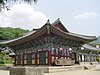 A square Asian-style building on an elevated stone base, with an extended and curved ornamental roof
