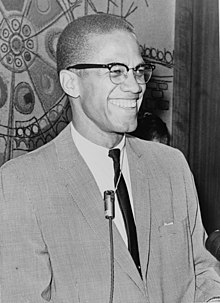 Photograph of Malcolm X smiling and wearing a suit