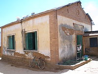 one-story brick and whitewashed schoolhouse with green wooden shutters and peaked roof