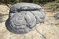 Altar "Monstruo de la Tierra del Norte", Cabeza labrada en relieve de un posible saurio con motivos celestes y terrestres.