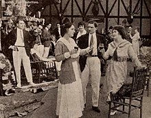 Film still, a courtroom scene, two women and one man in foreground.