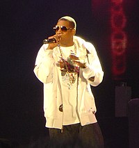 Jay-Z performs with a microphone and looks to his right.