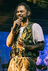 Miguel performing in a white shirt with a green vest and pants.