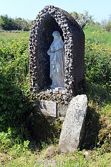 The modern statue and ancient cross-slab at Saint Bridget's well in Cliffoney village.