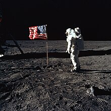 Un astronaute regarde le drapeau américain.