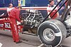 Man crouched working on drag racing car engine