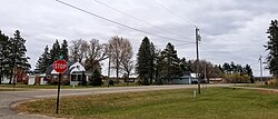 intersection of two two-lane roads with a stop sign and a few homes