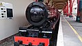 Maroon coloured miniature locomotive sits in the station