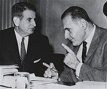Black and white image of representatives Oren Harris (left) and Steven Derounian (right) conferring during the House Subcommittee on Legislative Oversight investigation of quiz shows
