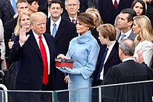 Trump, with his family watching, raises his right hand and places his left hand on the Bible as he takes the oath of office. Roberts stands opposite him administering the oath.