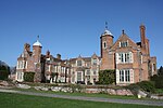 Kentwell Hall including detached building to the west, brick revetment of moat and two bridges over moat.