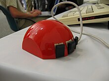 Hémisphère rouge garnie de trois boutons noirs à sa base et d'un fil posé près d'un clavier d'ordinateur