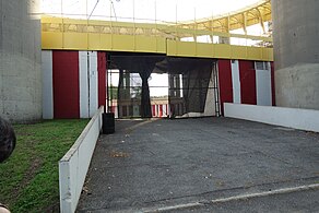 The entrance to the Tent of Tomorrow. The wall on either side of the entrance is red and white, and there is a yellow railing above.