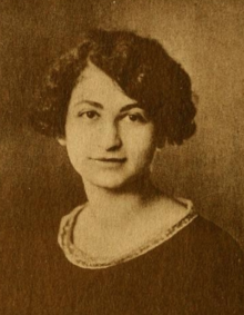 A young white woman with dark curly hair cut in a bob with a side part