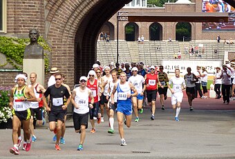 Klockan 13.48 den 14 juli 1912 gick starten för det olympiska maratonloppet i Stockholm. Alexis Ahlgren från Trollhättan tog täten inne på Stadion. Till höger: Jubileumsmarathon 2012-07-14, klockan 13.50 lämnade löparna Stadion och svänger in på Valhallavägen.