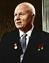 An elderly man in a suit, with three medals pinned on it