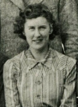 Photographie en noir et blanc d'une femme portant un chemisier à rayures, aux cheveux bouclés.