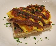 Scotch woodcock garnished with anchovy fillets and parsley. The anchovy paste is beneath the anchovy fillets.