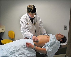 A medical trainee examining the abdomen of a Standardized Patient