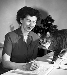 Cleary at her desk writing, joined in the photo by her cat.