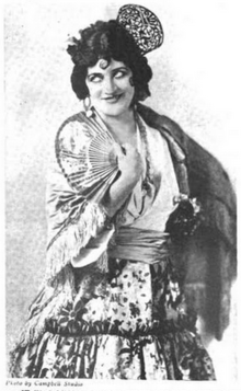 A smiling white woman with hair in curled style, wearing dressed as Carmen for the opera role