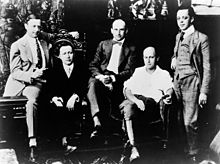 Five well-dressed men seated or standing at various levels