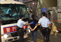 Police officers taking a woman on a police car after finding a utility knife on her body