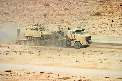 An Oshkosh M1070A1 HET and a DRS M1000 semi-trailer hauling a M2 Bradley IFV