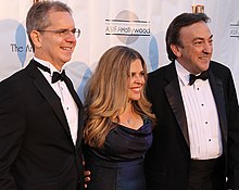 A smiling, formally-dressed Chris Buck, Jennifer Lee and Peter Del Vecho