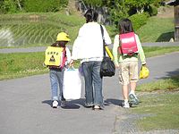 Two sisters wearing pink randoseru. One of them with a yellow plastic cover worn by 1st graders.